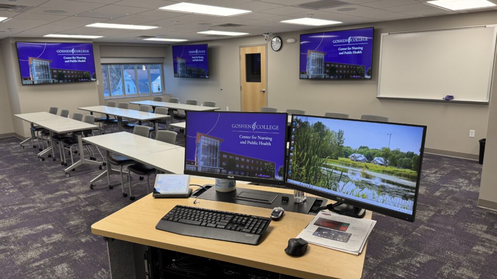 Dual monitor lectern looking at three TV displays around the room