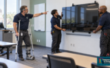 Two people mounting a TV and one directing them with an injured foot